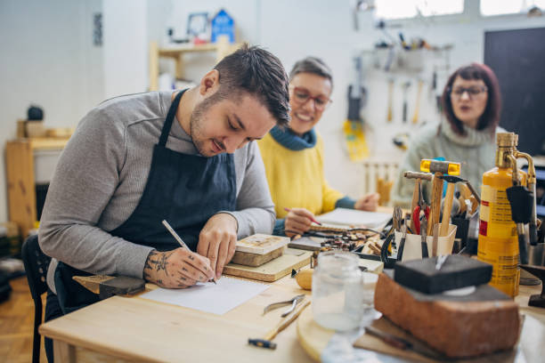 istock Focused man drawing in workshop classroom with peers 2167543373