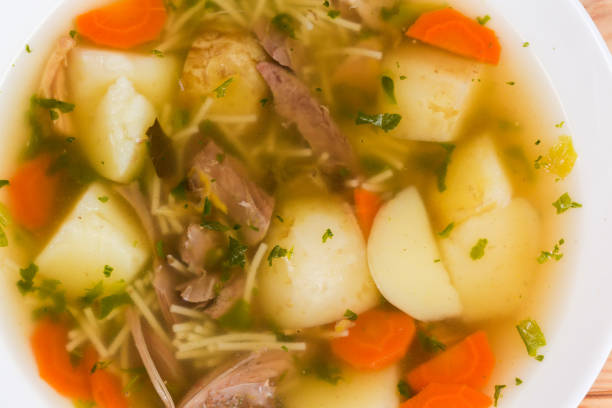 Freshly prepared hot homemade chicken soup with thin short vermicelli, top view of fragment close-up
