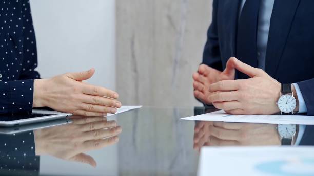 Unrecognizable business people shaking hands and clapping over glass table after contract signing in office. Agreement and handshake themes