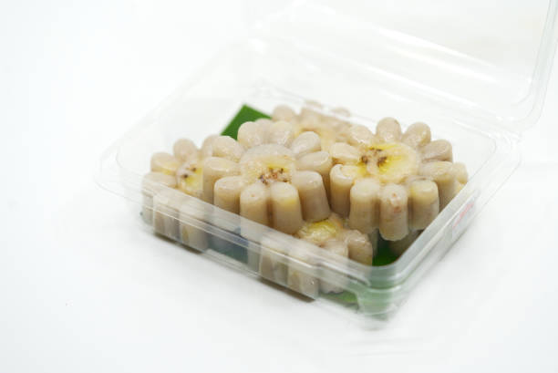 The healthy Thai snack made from fresh banana and coconut milk called Kanom Gloy or streamed banana cake. The streamed banana cake with flower shape in cleared plastic package on white background.