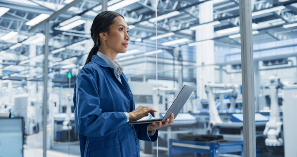 istock Portrait of a Beautiful Electronics Manufacturing Technician Working on a Laptop Computer at a Factory. Asian Female Specialist Developing, Maintaining, Setting Up Programs for Machine Production 2167547518