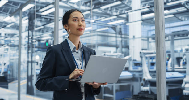 istock Thoughtful Asian Engineer Monitoring and Analyzing Conditions at a Pristine Modern Electronics Factory with Automated Robot Hands Working with Help of Artificial Intelligence Software 2167549106