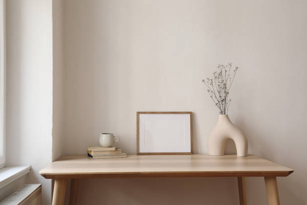 istock Horizontal empty wooden picture frame mockup. Boho shaped vase, dry flowers on table. Cup of coffee, old books. Working space, home office. Art, poster display. Modern interior. Beige wall background. 2167551668