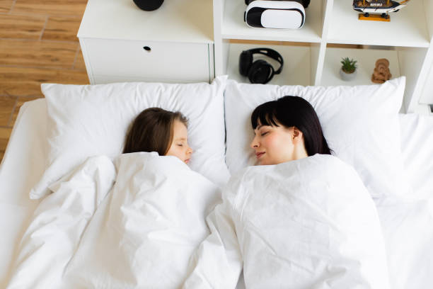istock Mother and daughter sleeping peacefully in white bedroom 2167552125