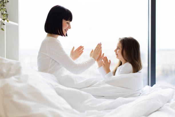 istock Mother and daughter playing clapping game in bed 2167552203