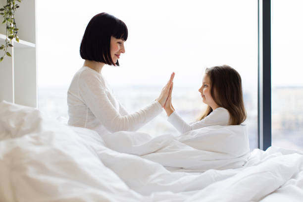 istock Mother and daughter playing together in bed with clapping hands 2167552210