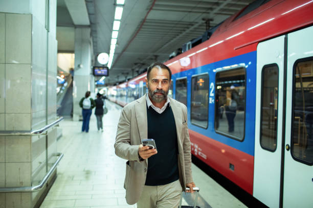 Close up of a Middle aged businessman using a smartphone while in a train station