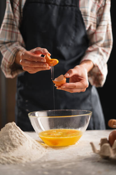 istock Woman separating egg yolk and egg white over transparent bowl in kitchen while cooking at home, close-up. Cooking protein dish, pastry, pastry with eggs. Kitchen, cooking food in kitchen. 2167555623