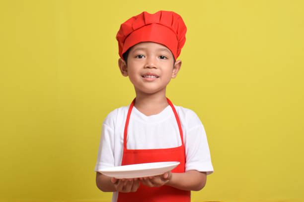 istock Asian boy wearing red apron. Cute little chef with plate 2167557847