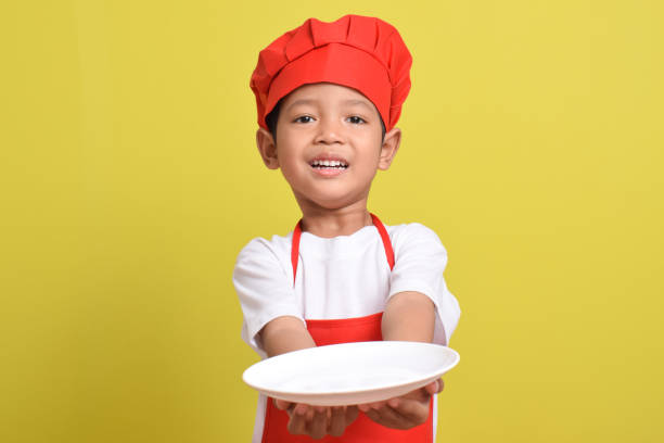 istock Asian boy wearing red apron. Cute little chef with plate 2167558310