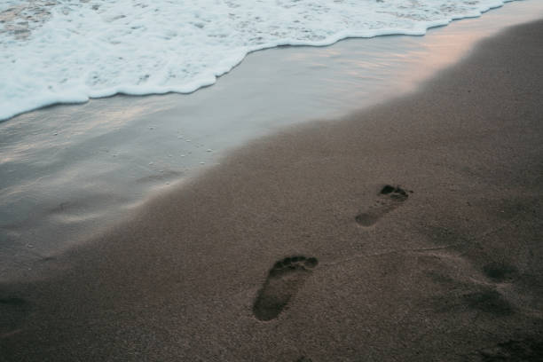 istock Men legs leaving footprints on the sandy beach. 2167560039