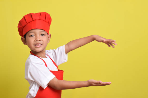 Cute little chef stretched out her hands to the side and smiles