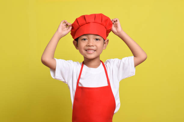 istock Cute little chef. Asian boy wearing red apron 2167561456