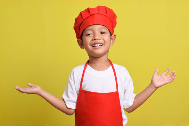 istock Asian boy wearing apron. Cute little chef with hand gesture aside 2167561942