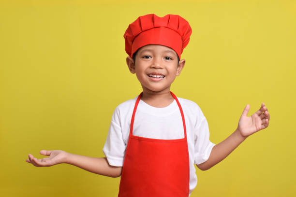 istock Asian boy wearing apron. Cute little chef with hand gesture aside 2167562031