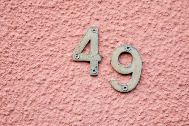 Number 49 on a pink coloured pebbledash wall