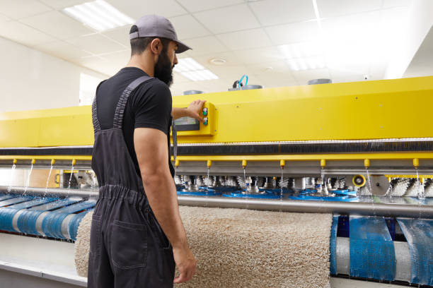 istock Man operating carpet automatic washing machine in professional laundry service 2167567064