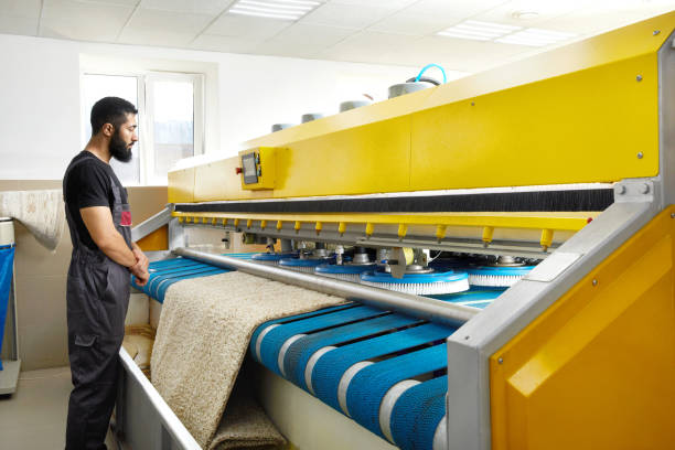 istock Man operating carpet automatic washing machine in professional laundry service 2167570110