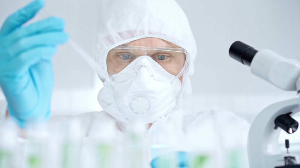 istock Professional scientist in protective gear is using pipette and examining a test tube in a laboratory setting 2167575199