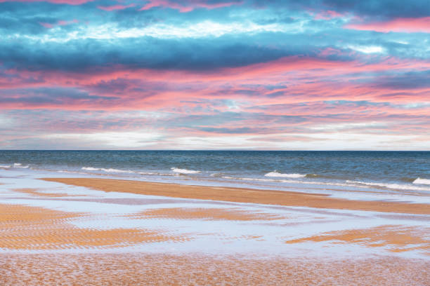 Tide waves on tropical beach sand and blue ocean water during sunset. Beauty sea texture. Vacations background
