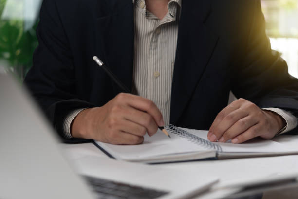 istock Businessperson writing notes in a notebook, emphasizing strategic thinking and planning. Ideal for business management content 2167577561