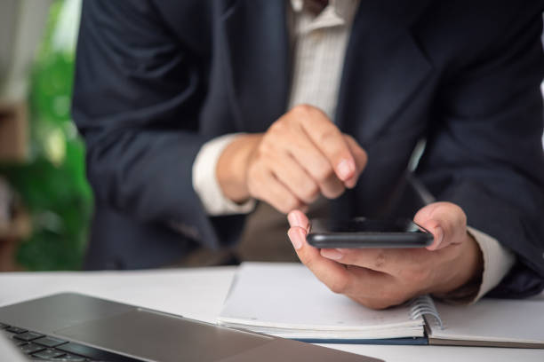 istock Businessman using a smartphone in an office setting, representing digital finance and communication. Suitable for fintech services, mobile banking apps 2167577562