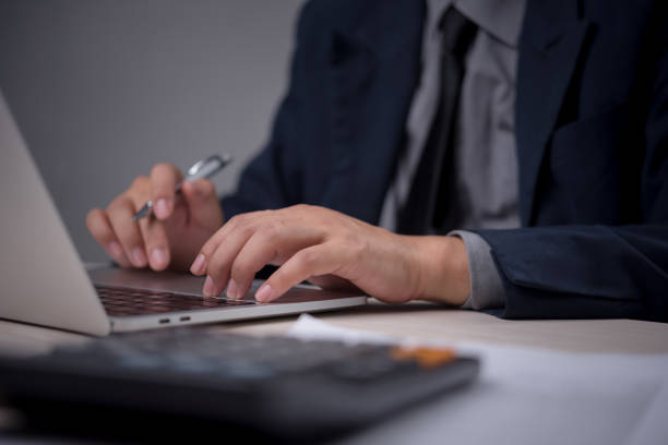 istock Businessperson typing on a laptop while holding a pen, symbolizing a focused work environment. Ideal for corporate presentations, business management 2167577588
