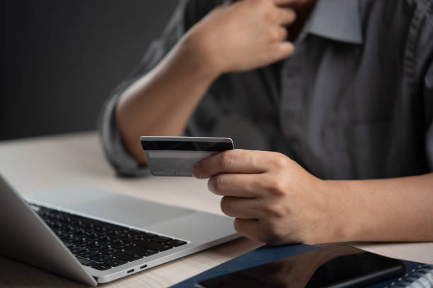 istock Person holding a credit card while using a laptop for online payment, representing e-commerce and digital transactions. Perfect for online shopping, fintech, and payment gateway services 2167577791