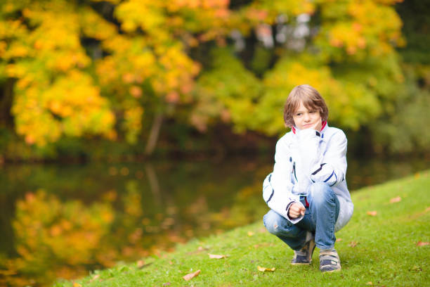 Kids play in autumn park. Children throwing yellow and red leaves. Little girl with oak and maple leaf. Fall foliage. Family outdoor fun in autumn. Toddler kid or preschooler child in fall.