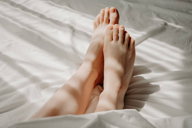 istock Woman is lying with bare feet in bed, sleeping under white cosy and comfortable bedclothes. Female feet on bed. Good morning, woman sexuality concept, self-care and relaxation, resting concept. 2167582764