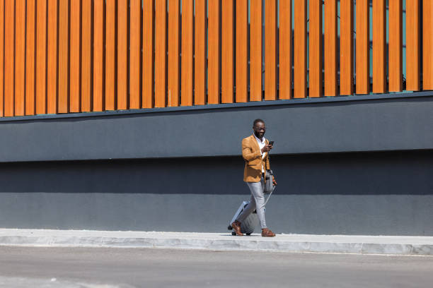 istock Businessman with suitcase walking and using phone 2167583819