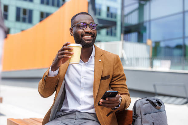 istock Smiling businessman enjoying a coffee break while using smart phone outdoors 2167583918