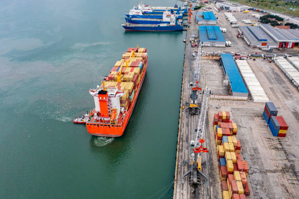 istock Aerial view of cargo container ship approaching port with Tugboat. 2167587743
