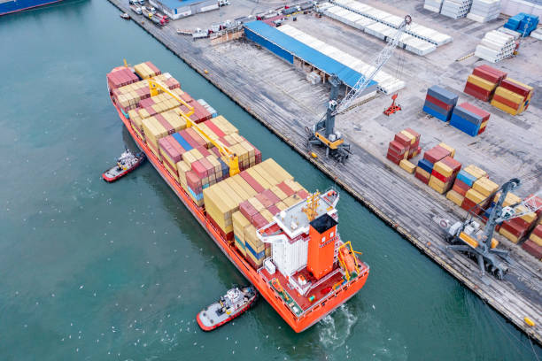 istock Aerial view of cargo container ship approaching port with Tugboat. 2167588484