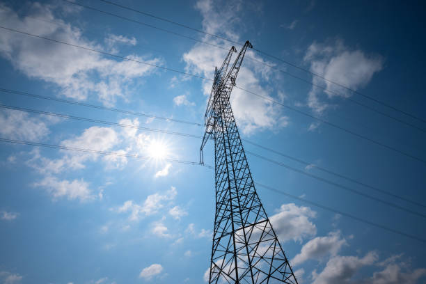 istock a high-voltage pylon, worm's-eye view, backlit with sun, blue sky and white clouds 2167590618