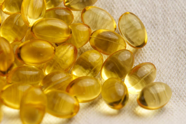 istock Golden soft gel capsules on a textile background. Nutritious vitamin pills 2167592282