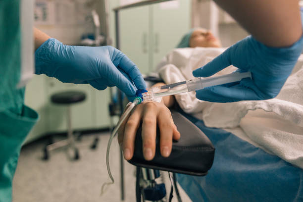 Operating room, medical concept The process of intravenous therapy with a focus on a patient's hand and the healthcare professional's gloved hands child liquid medicine stock pictures, royalty-free photos & images