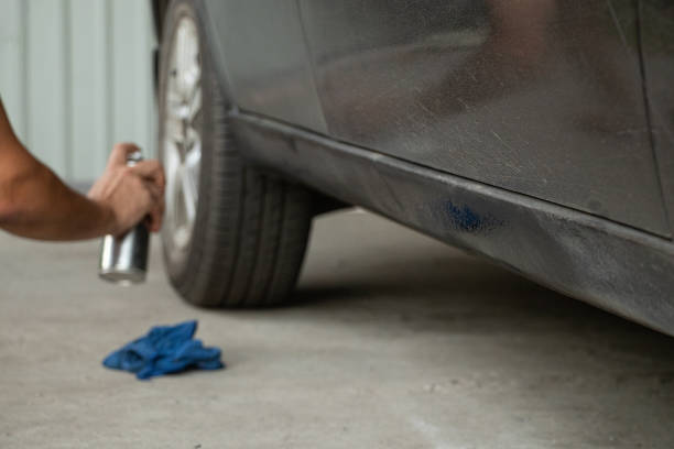 istock A man spray paints a car in a yard with black paint 2167597446