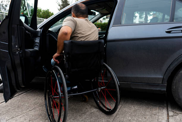 man with a wheelchair, 30 to 40 years old, moving from his chair to his car.