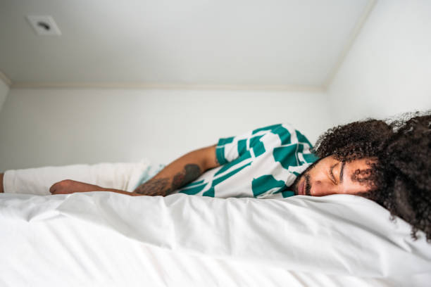 istock Young man sleeping in bed in a hostel room 2167605043