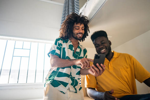 istock Gay couple using the mobile phone in a hostel room 2167605075