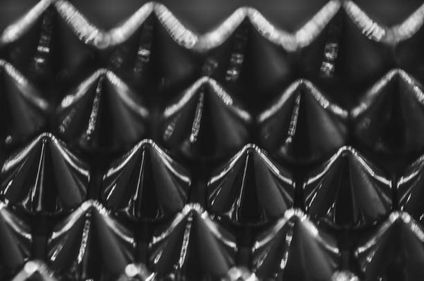 Close-up macro of sewing studs arranged in symmetrical rows in black and white abstraction
