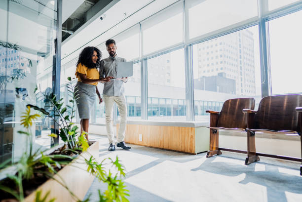 istock Coworkers talking and using laptop while walking through the office 2167605584