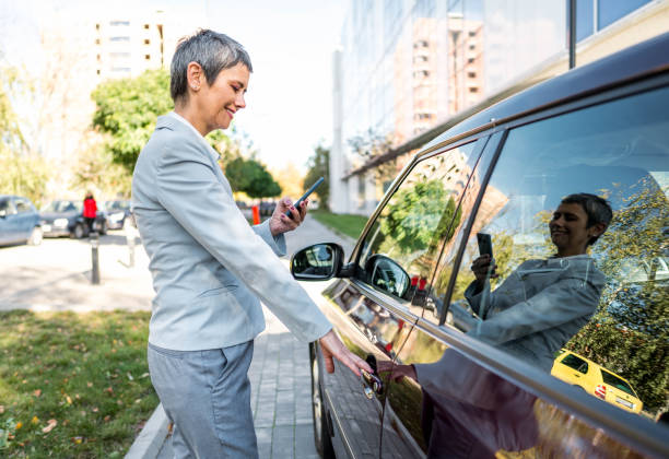 istock Businesswoman using phone while getting into the car 2167608018