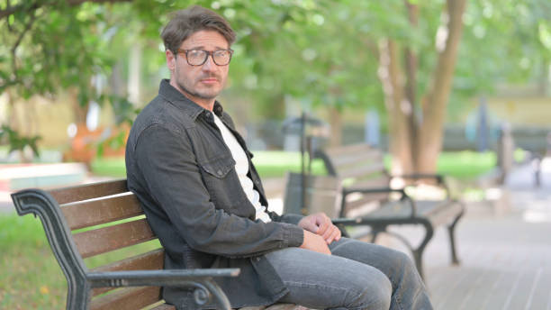 istock Middle Aged Man Looking at Camera while Sitting Outdoor 2167609542