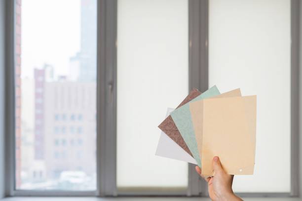 istock Woman holding fabric samples of roller blinds against window background. 2167609820
