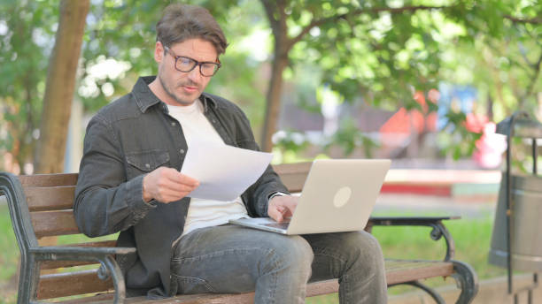 istock Middle Aged Man Working with Documents and Laptop Outdoor 2167612721