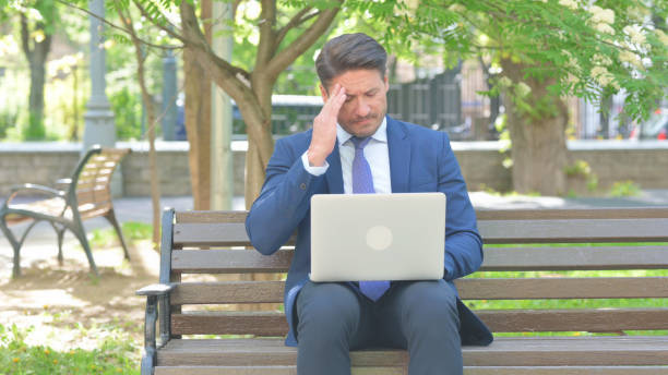 istock Middle Aged Businessman with Headache Using Laptop, Sitting Outdoor 2167613508