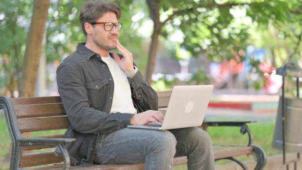 istock Middle Aged Man with Toothache Using Laptop Outdoor 2167614844