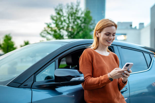 istock Female driver using smart phone by her car in the city 2167615552